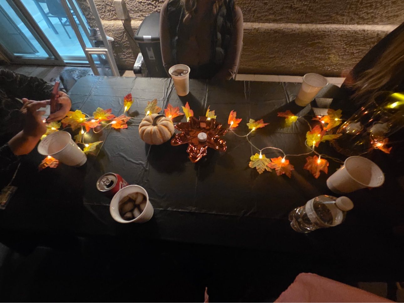 Fall-themed table with black tablecloth and light-up leaf garland by July's Rentals